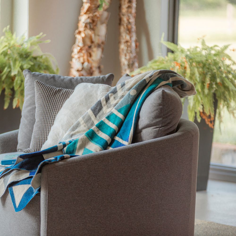 A gray couch adorned with a blue and white blanket draped over the armrest.