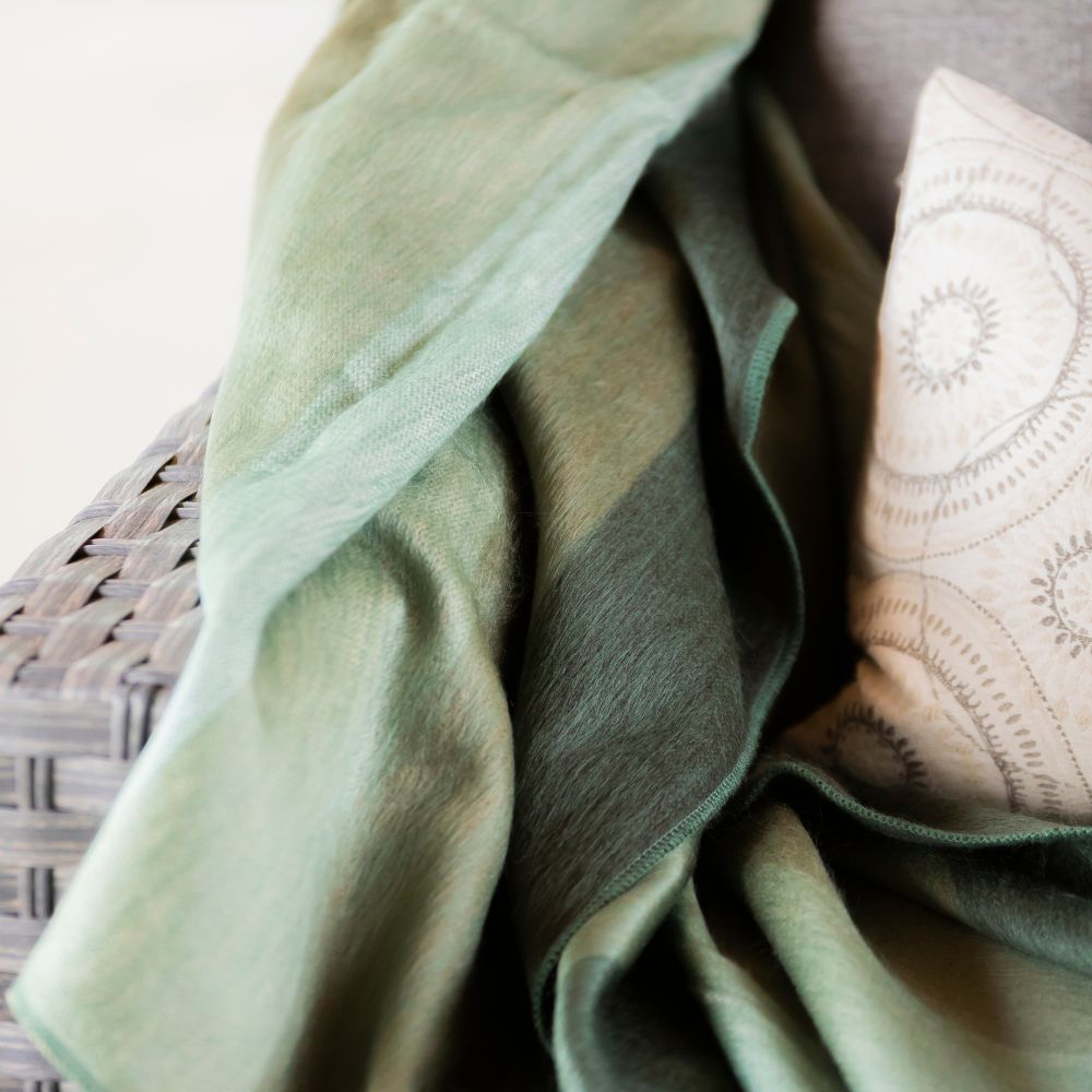 A green and white blanket draped over a pillow, creating a cozy and inviting bedding arrangement.