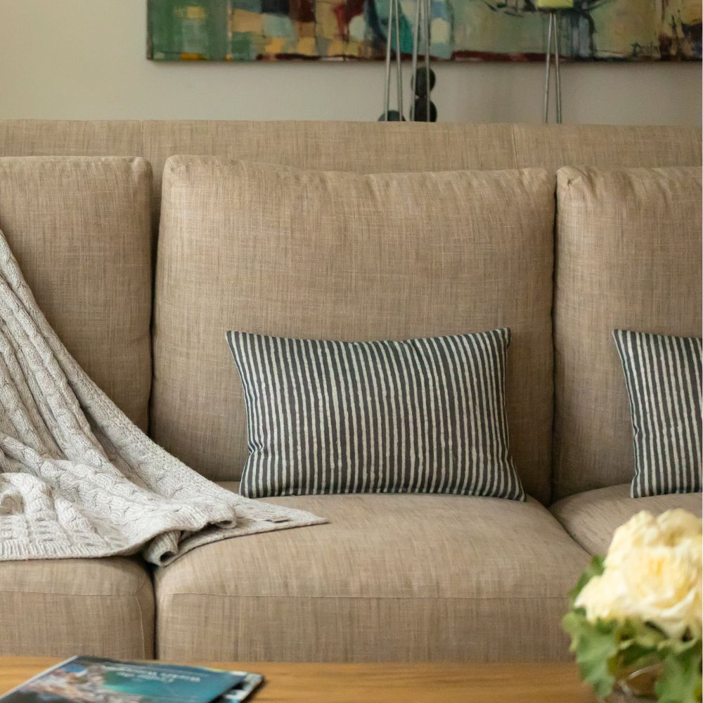 A cozy couch adorned with a colorful blanket and a vase of fresh flowers on its surface.