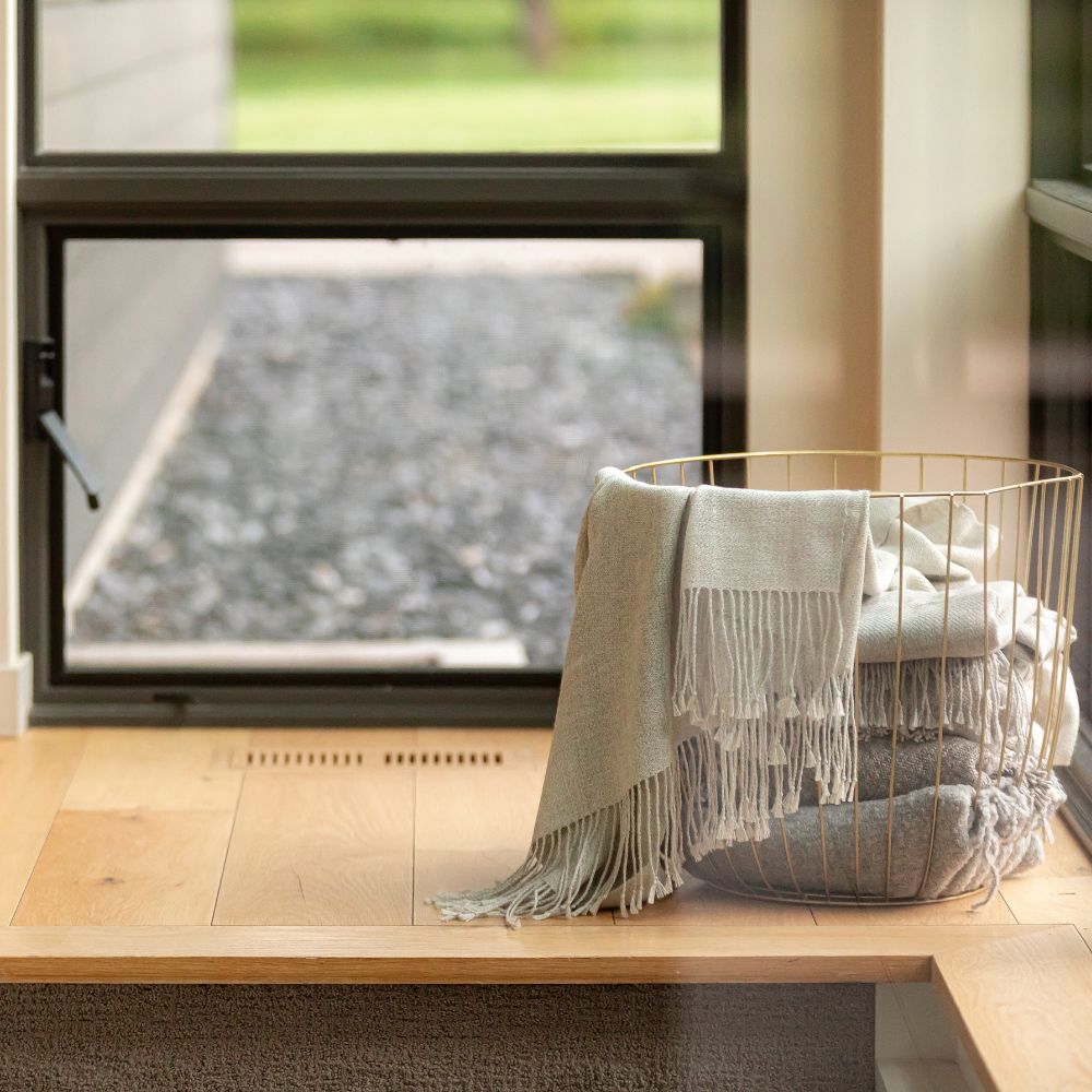 A basket filled with neatly folded towels rests on a sunlit window sill, adding a cozy touch to the room.
