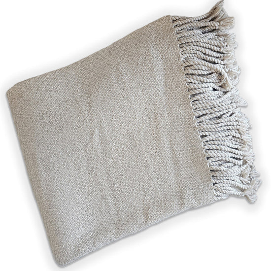 Gray woven blanket with fringed edge on a white background