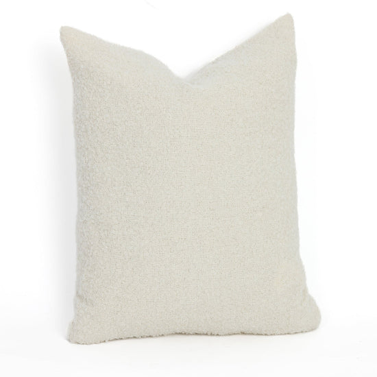 A square-shaped, ivory-colored bouclé pillow with a knobby texture, made from alpaca and polyamide fibers.