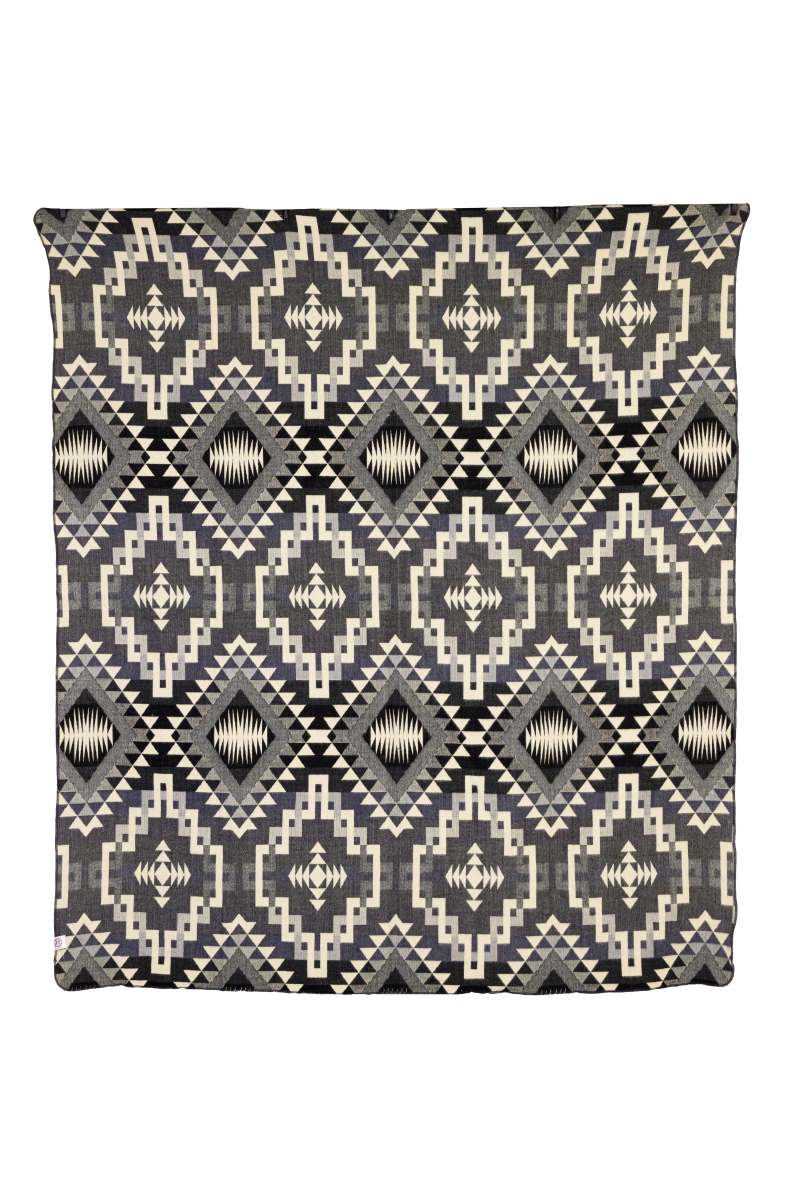 A woven throw blanket featuring an interlocking lines geometric pattern in gray, black, and cream colors.