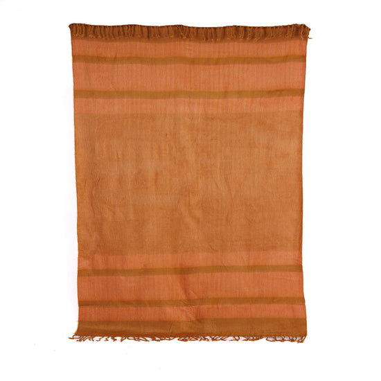 A copper and coral colored throw blanket with hand-tied tobacco colored fringe on the long ends, displayed against a plain background.