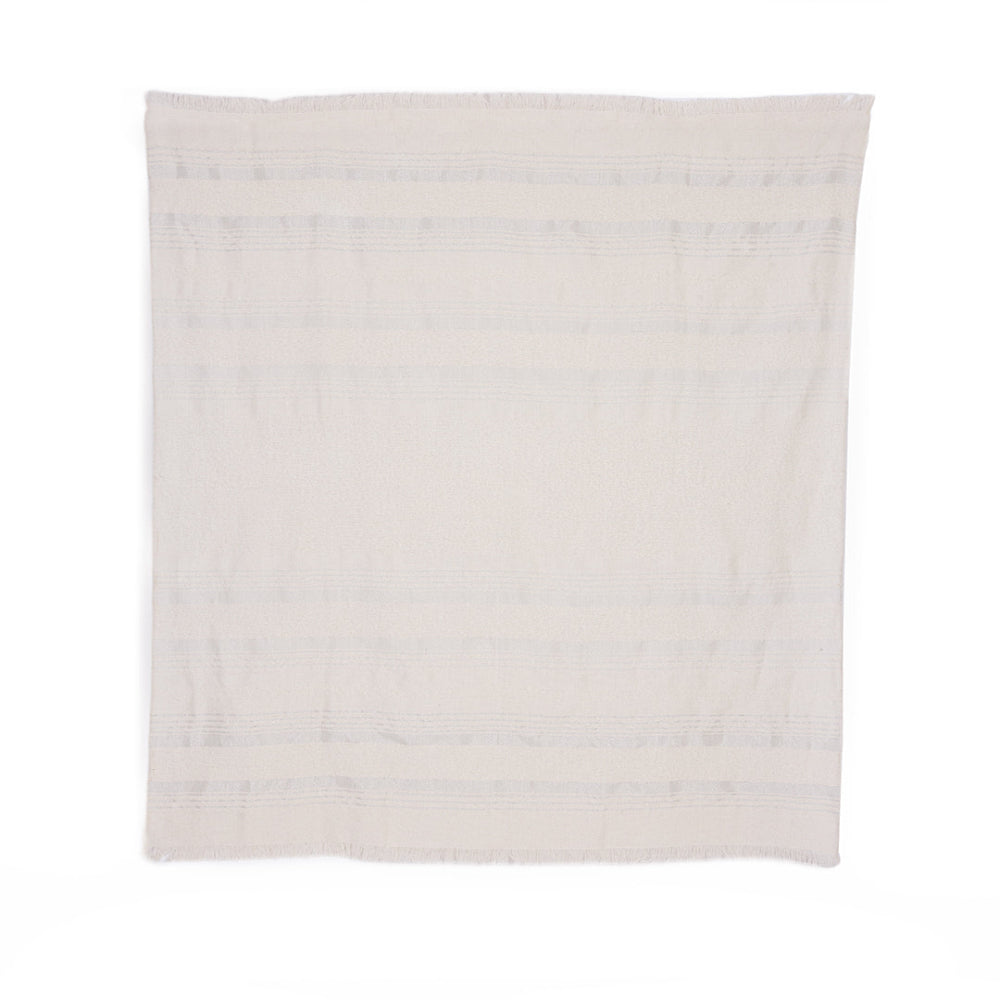 A handloomed alpaca throw in silver and ivory colors with a subtle striped pattern and boucle texture.