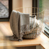 gray throw blanket with fringe in wire basket