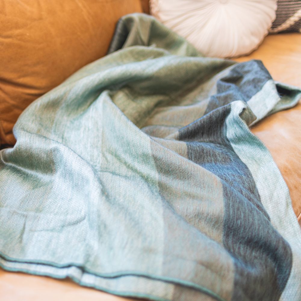 Green and blue striped throw on tan couch pillow