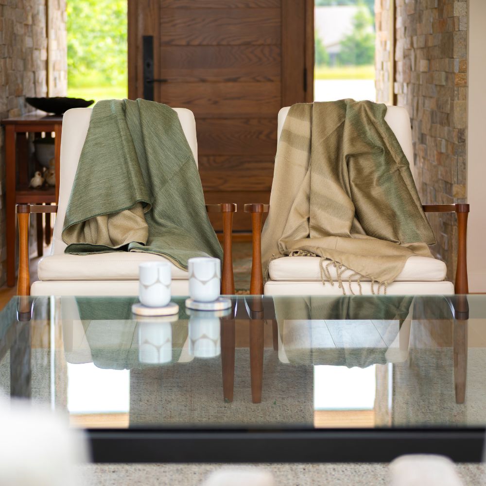 Two white chairs with blankets beside glass table in cozy room