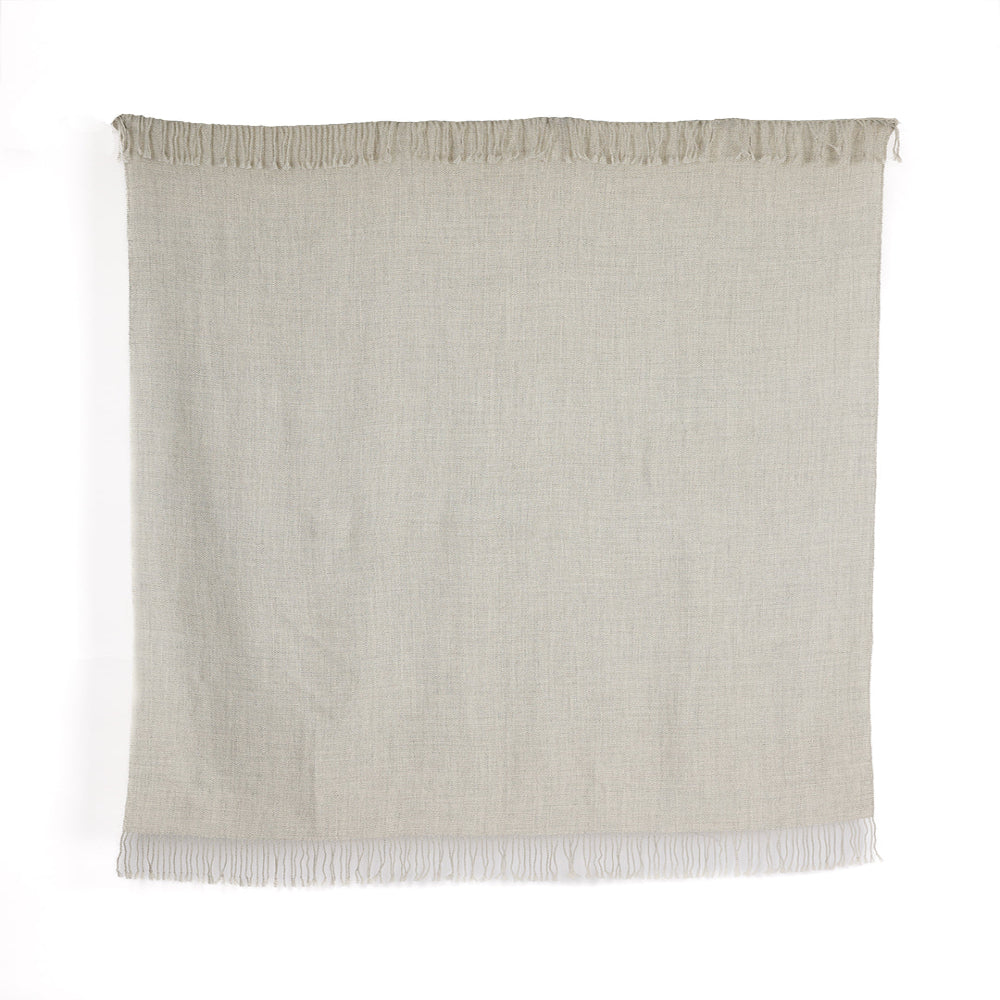 A rectangular undyed silver baby alpaca throw with fringes, handwoven and displaying the natural fiber colors from the alpaca's fur.
