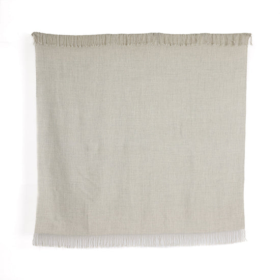 A rectangular undyed silver baby alpaca throw with fringes, handwoven and displaying the natural fiber colors from the alpaca's fur.